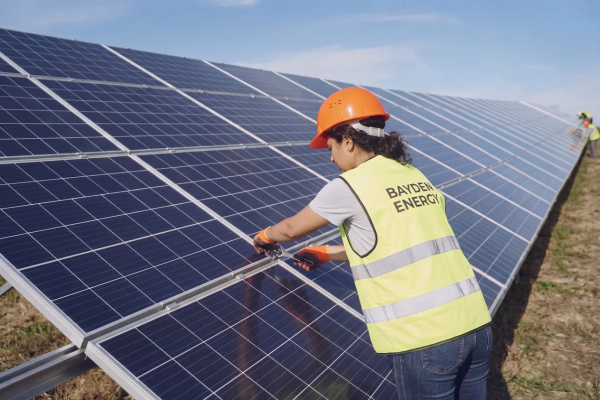 Technician in a Bayden Energy vest working on a solar panel array
